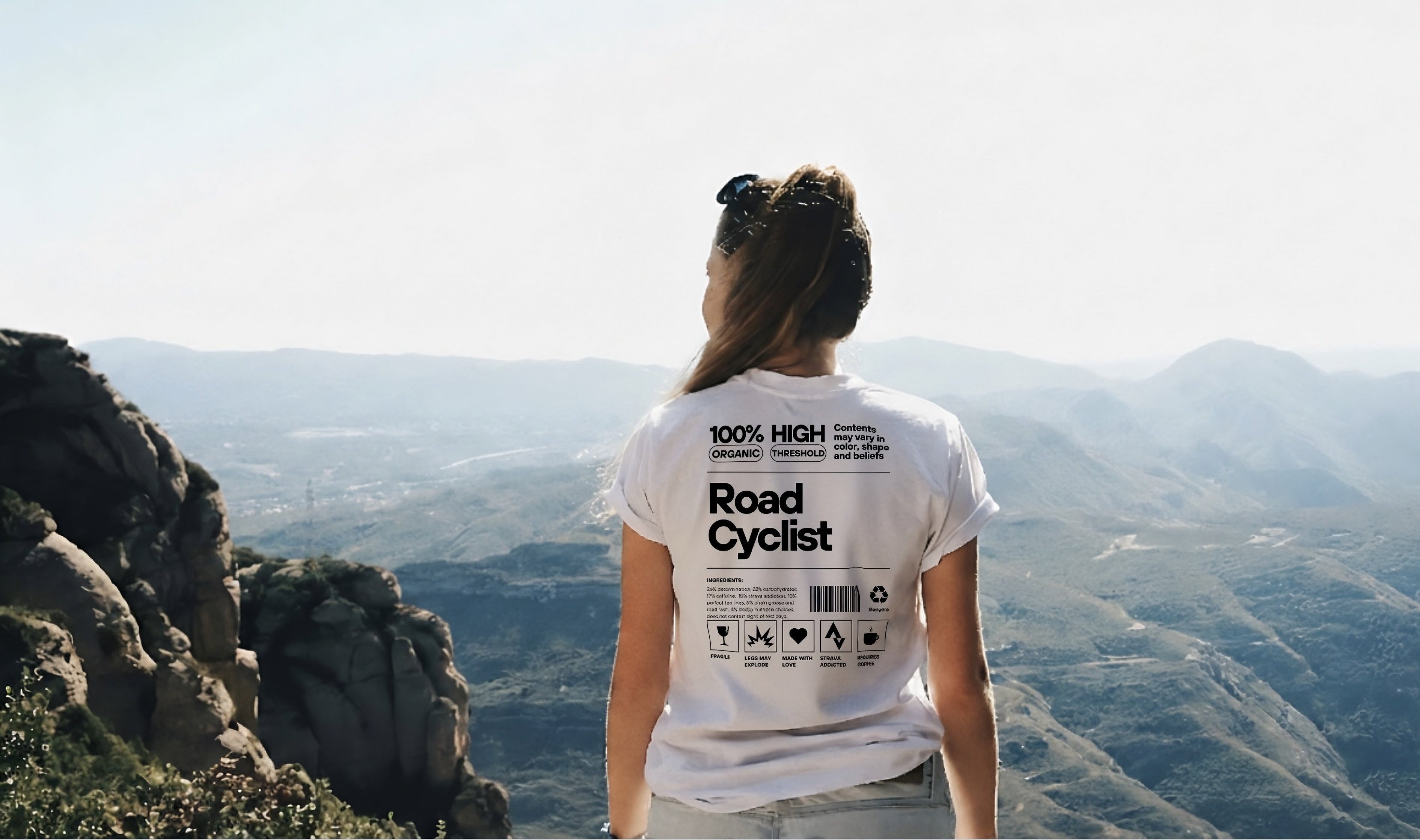 Person wearing a 'Road Cyclist' t-shirt overlooking a scenic landscape