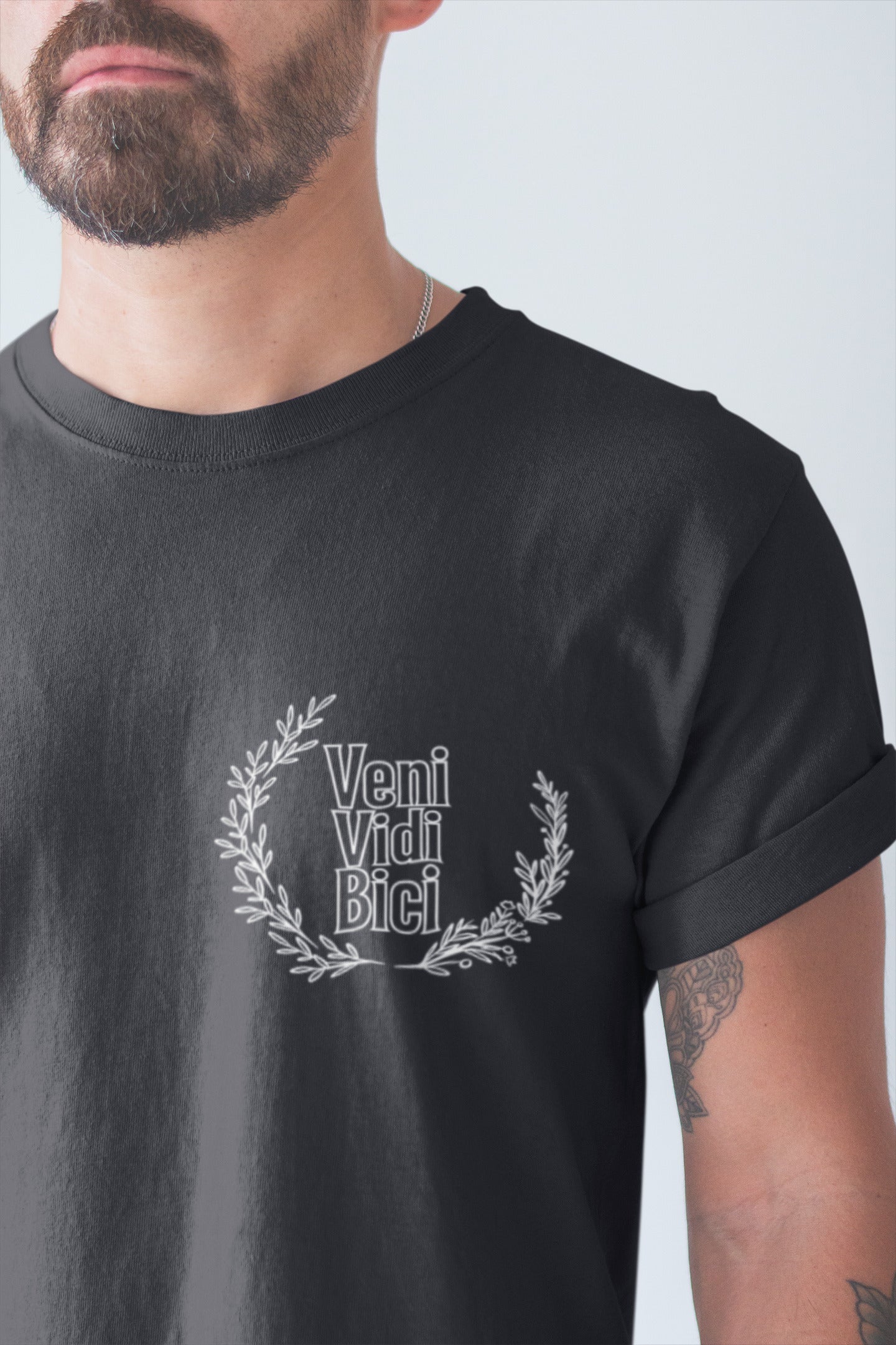 Person wearing a black t-shirt with 'Veni Vidi Bici' design on a plain background
