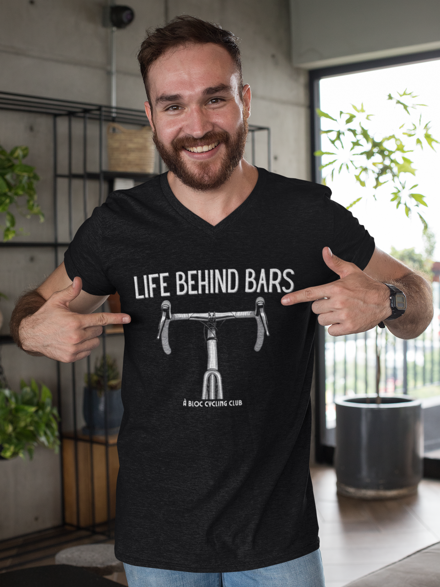 Man wearing a black t-shirt with 'Life Behind Bars' graphic and text, pointing at the design.